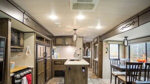 Una cocina moderna con una isla central, electrodomésticos integrados y un comedor con muebles de madera.