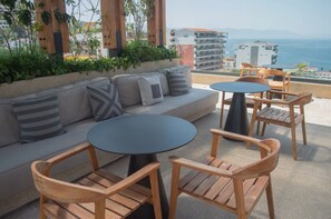 A terrace with a sofa, two round tables, and wooden chairs. - Amazing Rooftop/Romantic Zone (Puerto Vallarta)