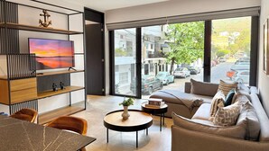 Ett modernt vardagsrum med tv, soffa, soffbord och utsikt över gatan.