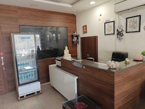 A reception area with a glass counter, a refrigerator, a wooden cabinet, and a reception sign.