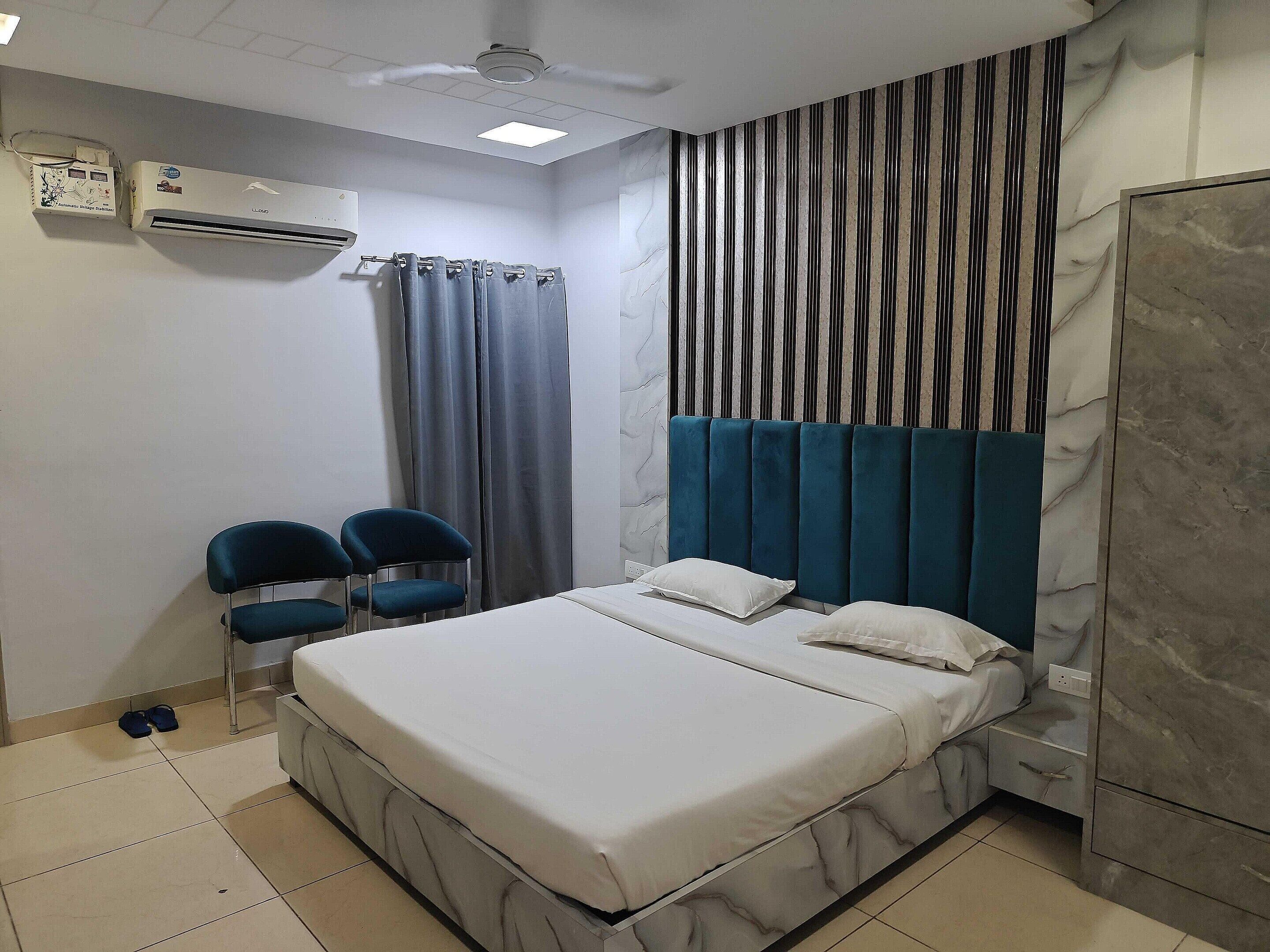 Un dormitorio con cama, dos sillas, un armario, un ventilador de techo y un equipo de aire acondicionado.
