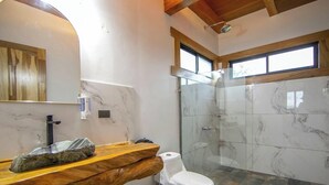 Ein Badezimmer mit einer Marmordusche, einem Holzkosmetikschrank und einer Toilette.