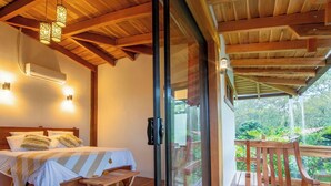 Ein Schlafzimmer mit Bett, Nachttisch und einem Fenster mit Blick ins Grüne.