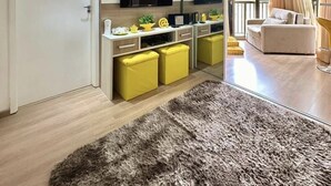 Et moderne køkken med indbyggede apparater, et spiseområde med gule stole og en stue med sofa og gardiner.