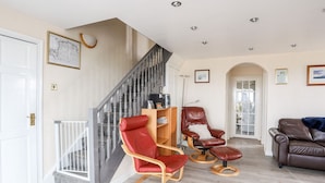 A living room with a staircase, leather chairs, a sofa, and a wooden coffee table. - Bodlasan Groes Cottage (Holyhead)