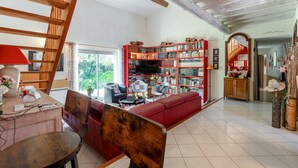 A spacious living room with a red sofa, a wooden staircase, and a bookshelf filled with books.