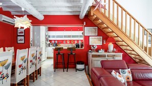 A dining area with a red wall, white ceiling, and a wooden staircase.
