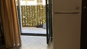 Eine Küche mit Kühlschrank, einer Uhr und einer Glastür zu einem Balkon.