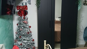 Ein Zimmer mit Weihnachtsbaum, Bett, Schrank und einem kleinen Tisch.