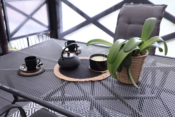 A table with a teapot, cups, and a potted plant.