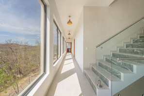 A modern interior with a glass staircase, large windows, and a hallway leading to a door. - NEW! Oceanview, Infinity Pool, Spacious & Private Luxury Group Retreat (Potrero)