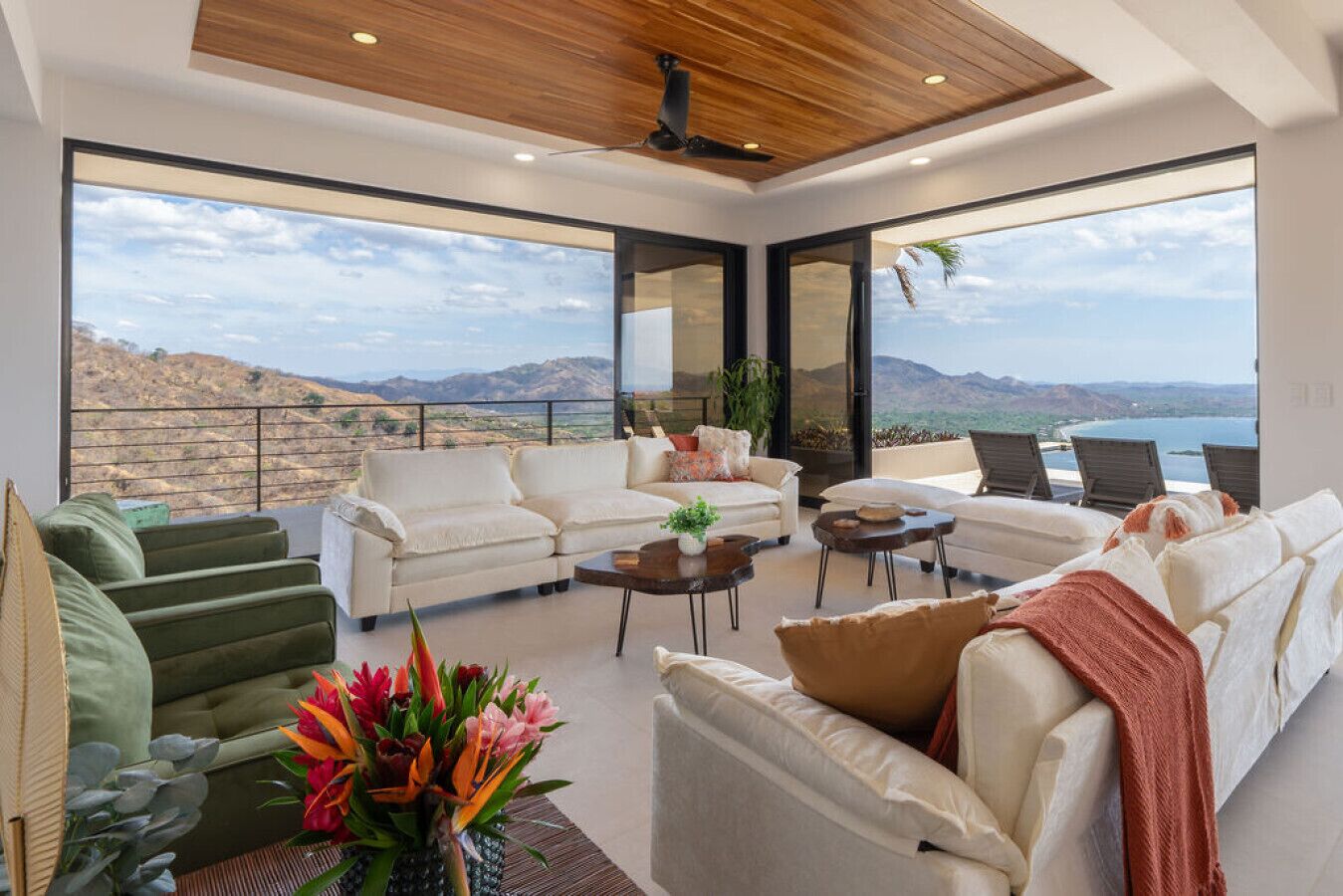 A spacious living area with a large window overlooking a scenic landscape, a ceiling fan, and a variety of seating arrangements.