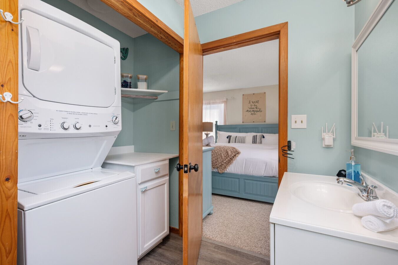 A laundry area with a washer and dryer, a bedroom with a bed and a nightstand, and a bathroom with a sink and mirror.