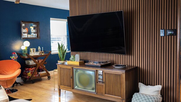 A living room with a television, wooden panel wall, and a small table with items. - 3-Bedroom house in tree-lined neighborhood in Millcreek (Salt Lake City)