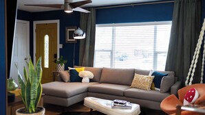 A living room with a sectional sofa, a ceiling fan, a window with blinds, and a potted plant. - 3-Bedroom house in tree-lined neighborhood in Millcreek (Salt Lake City)