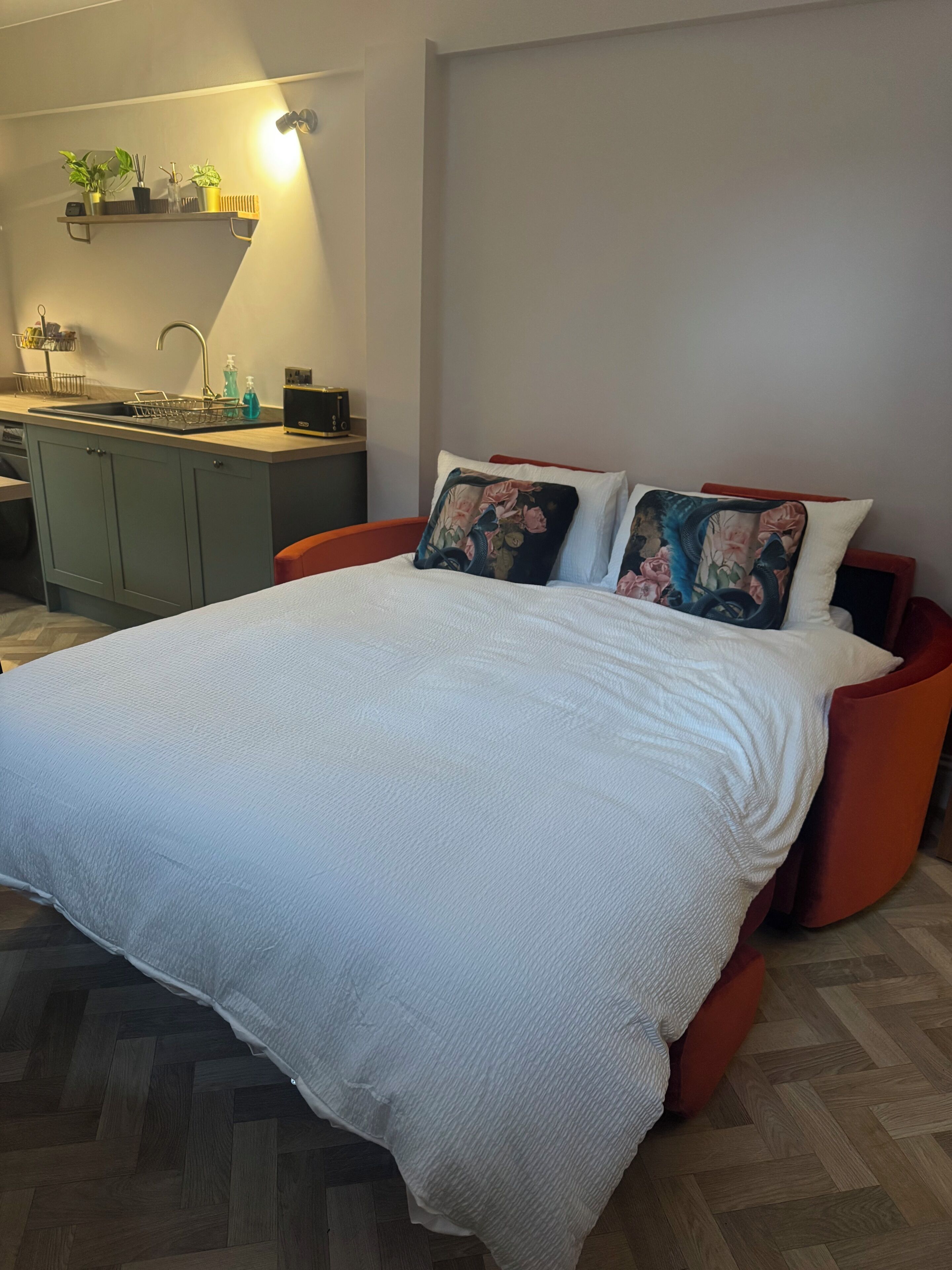 Een moderne slaapkamer met een bed, nachtkastje, bureau en een plank met planten.