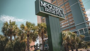 A sign for McGure's Irish Pub with a modern building in the background. - Sunnyside Up in PCB (Panama City Beach)