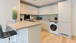 A modern kitchen with a central island, built-in appliances, and a washing machine. - Liverpool Richmond Row 2 Bed/2 Bath Flat (107)| Secure Parking, WiFi & EV (Liverpool)
