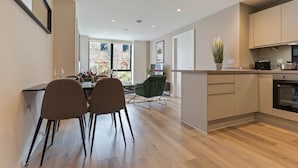 A modern kitchen with a dining area, wooden flooring, and a view of the outside. - Liverpool Richmond Row 2 Bed/2 Bath Flat (107)| Secure Parking, WiFi & EV (Liverpool)