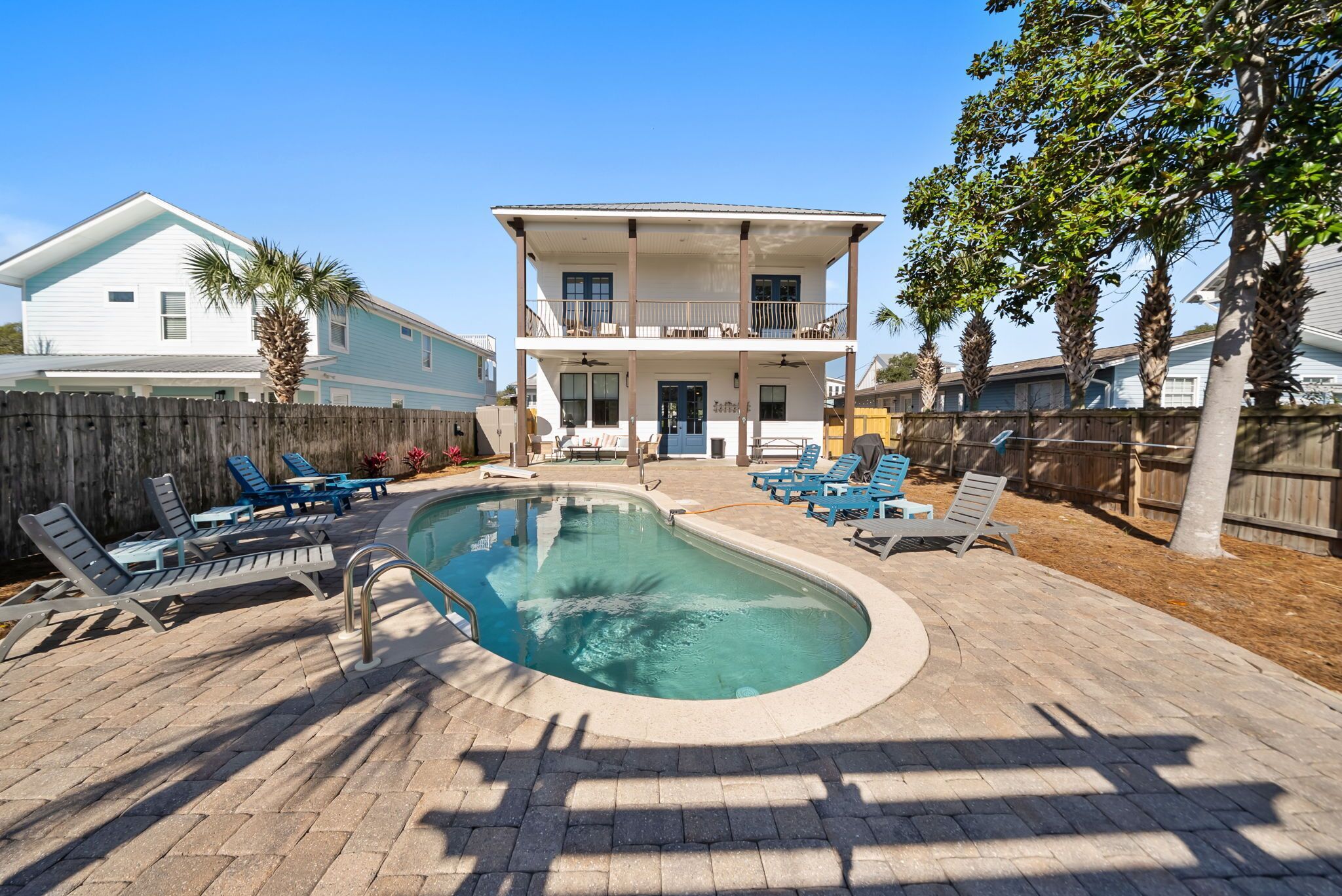 A two-story building with a swimming pool and lounge chairs.
