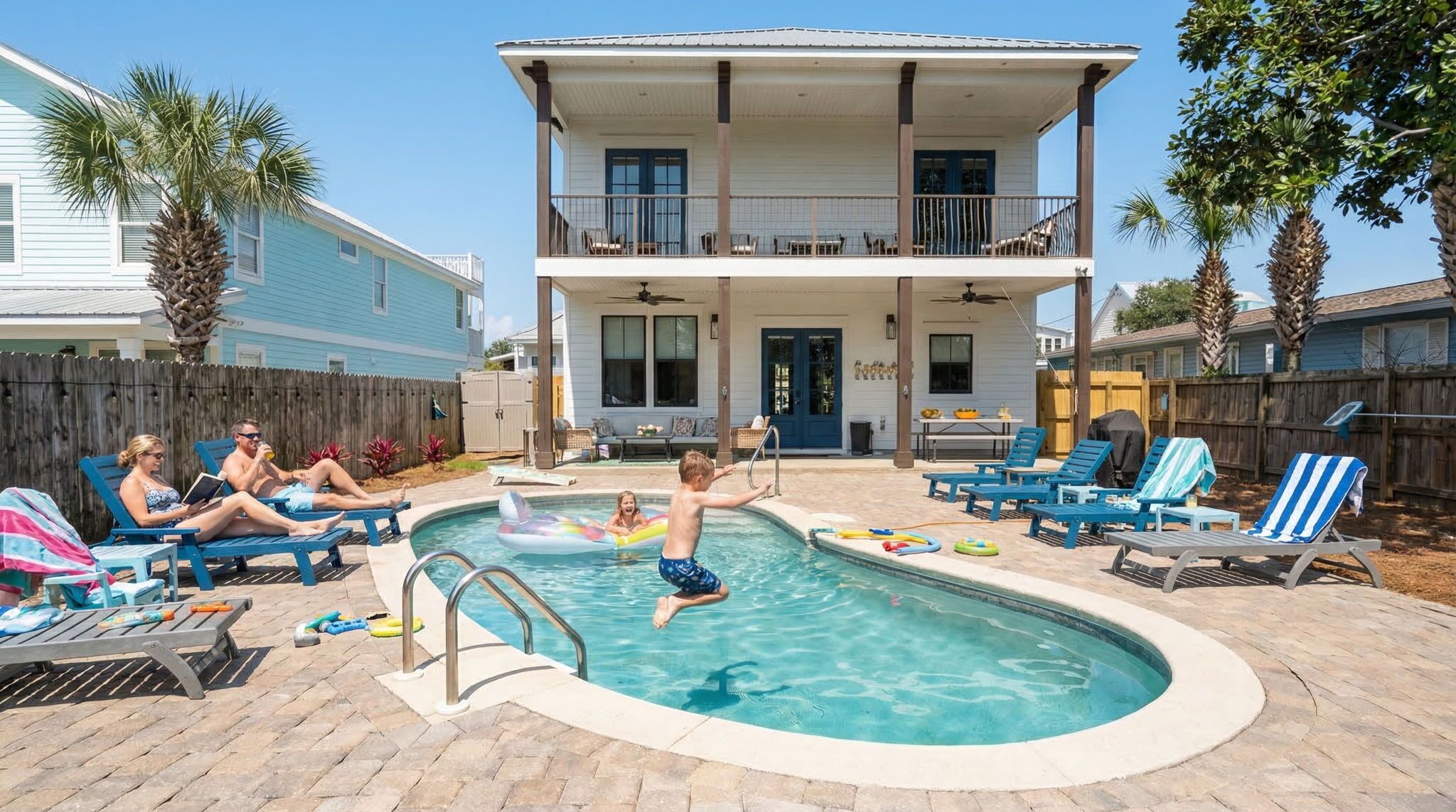 A swimming pool with lounge chairs and a two-story house in the background.