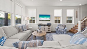 A living room with a sofa, armchair, coffee table, and a painting of a beach scene. - Take It Easy (Destin)