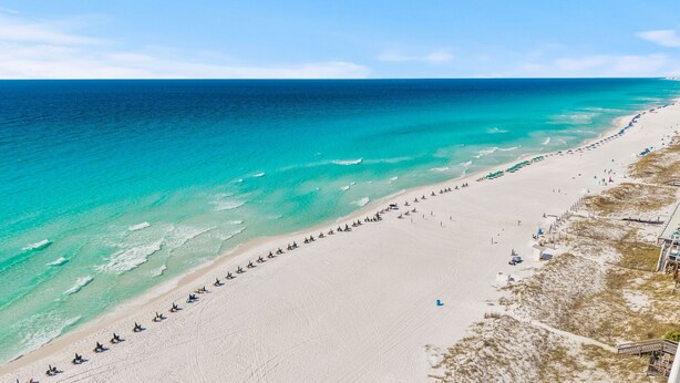 A beach with a long stretch of white sand, clear turquoise water, and a few beach umbrellas. - Take It Easy (Destin)