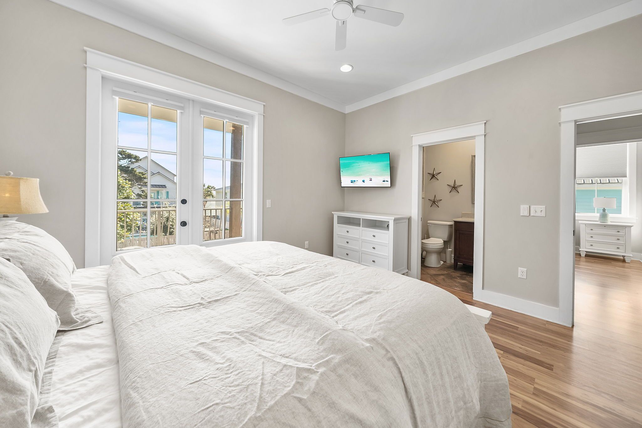 A bedroom with a bed, a TV, a dresser, and a bathroom visible through an open door.