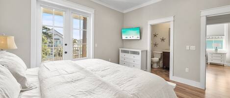 A bedroom with a bed, a TV, a dresser, and a bathroom visible through an open door.