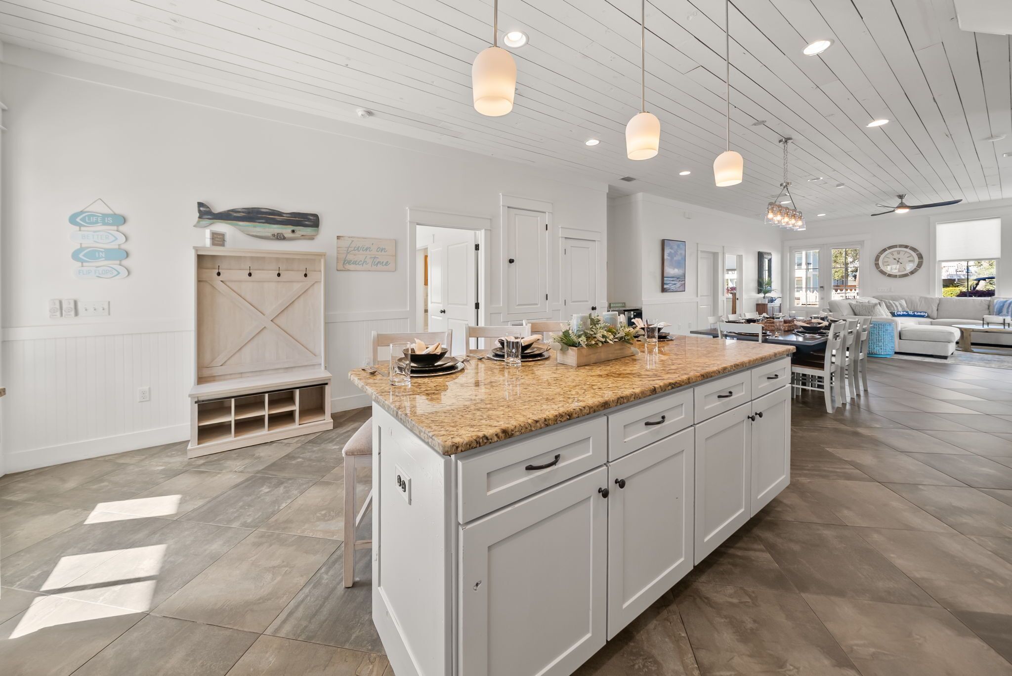 A spacious kitchen with white cabinetry, a granite countertop, pendant lighting, and a large island.