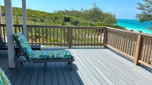 A wooden deck with two lounge chairs and a view of the ocean. - New Oceanfront Beach House, "Paradise Blue" - Your Private Tropical Escape. (Rolleville)
