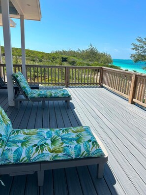 Eine Holzterrasse mit zwei Liegestühlen und Blick auf das Meer.