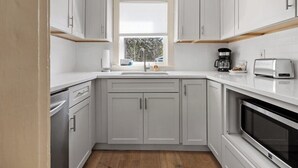A modern kitchen with white cabinets, a built-in oven, a coffee maker, and a toaster. - Lone Star-New! Sleep 8 in Seal Harbor! (Mount Desert)