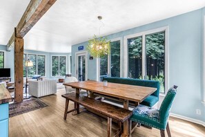 A dining area with a wooden table, benches, and a teal upholstered chair. - Reef Point Cottage-Ocean views! (Bar Harbor)