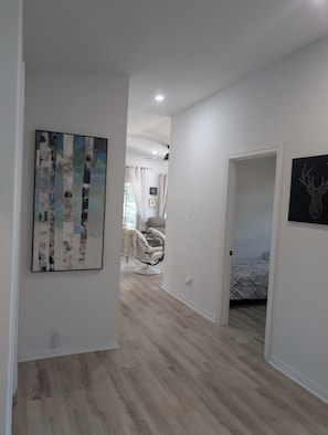 Un pasillo con un cuadro de abedules, una cama con colcha estampada y una obra de arte de cabeza de ciervo en la pared.