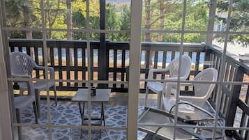A covered outdoor seating area with a view of trees and a body of water.