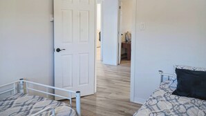 A bedroom with two beds, a ceiling fan, and a door leading to another room.