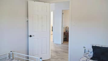 A bedroom with two beds, a ceiling fan, and a door leading to another room.