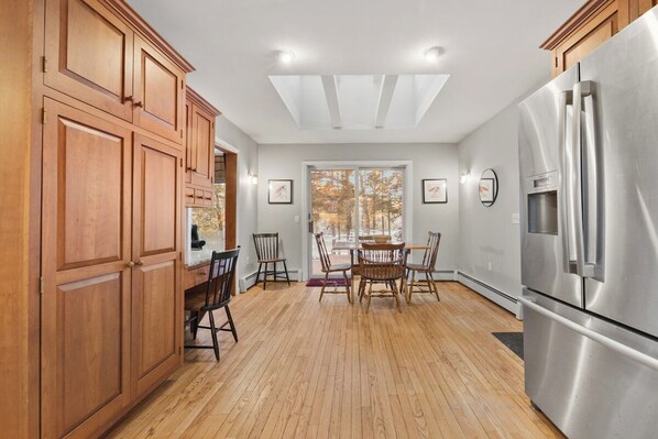 A kitchen with wooden cabinets, a stainless steel refrigerator, and a dining table with chairs. - Branchview Shores-Lakefront! (Ellsworth)