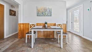 Et spiseområde med en træbænk, et bord og et billede på væggen.