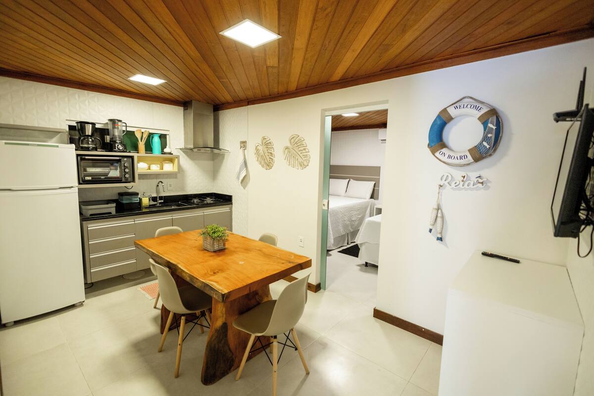A compact kitchen with a wooden table, chairs, and a refrigerator.