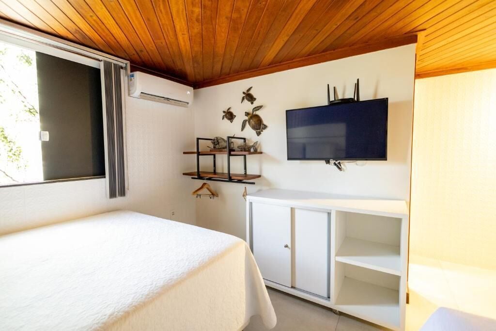 A room with a bed, a TV mounted on the wall, and a white cabinet.
