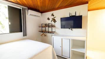 A room with a bed, a TV mounted on the wall, and a white cabinet.