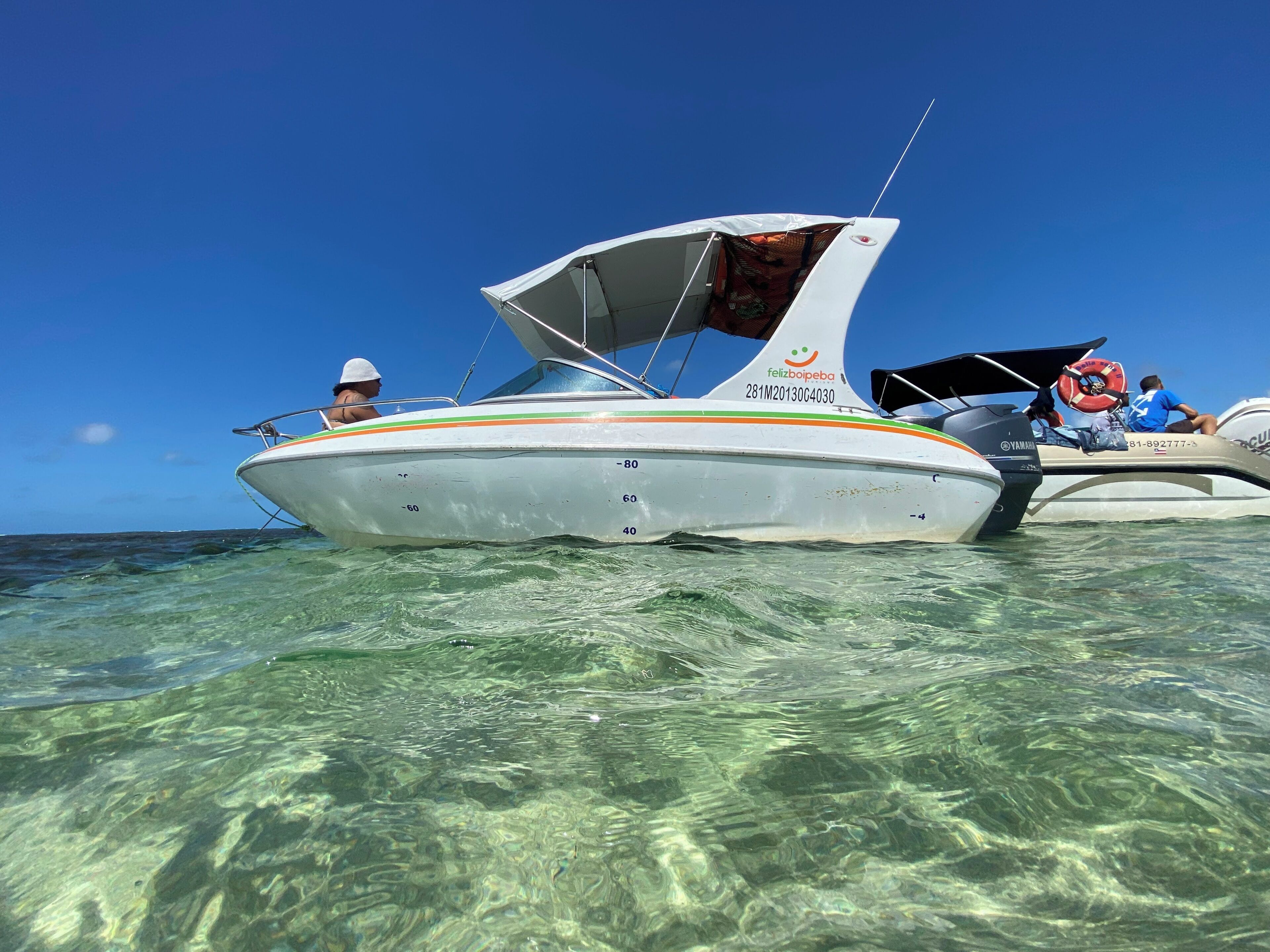 Um barco com número de registro, um motor Yamaha e uma pessoa usando chapéu branco.