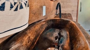 A bathroom with a wooden sink, a towel, and a wall-mounted light fixture. - Pousada Feliz Boipeba Apartamentos (Cairu)