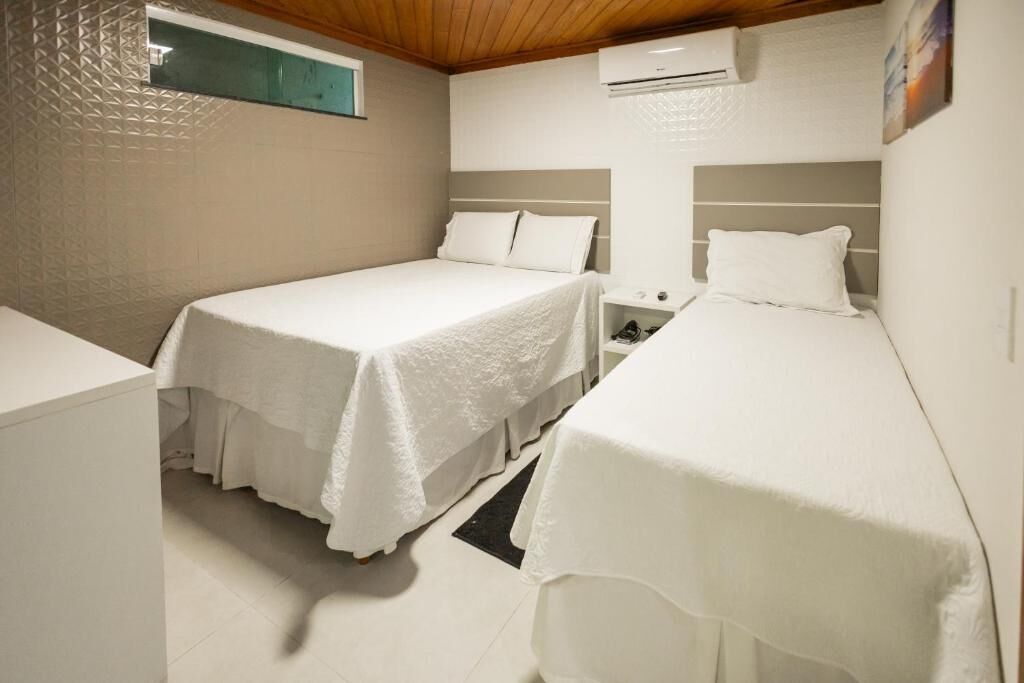 Un dormitorio con dos camas, una mesita y un aire acondicionado.