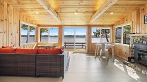 A wooden cabin interior with a sofa, dining table, and fireplace.