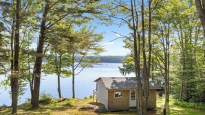 A small cabin by a lake surrounded by trees.