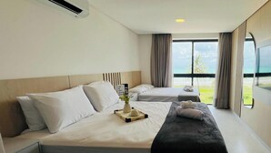 Una habitación de hotel con dos camas, un ventanal con vistas y un equipo de aire acondicionado.