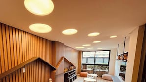 Un interior moderno con paneles de madera, una escalera, una zona de estar y un ventanal grande.